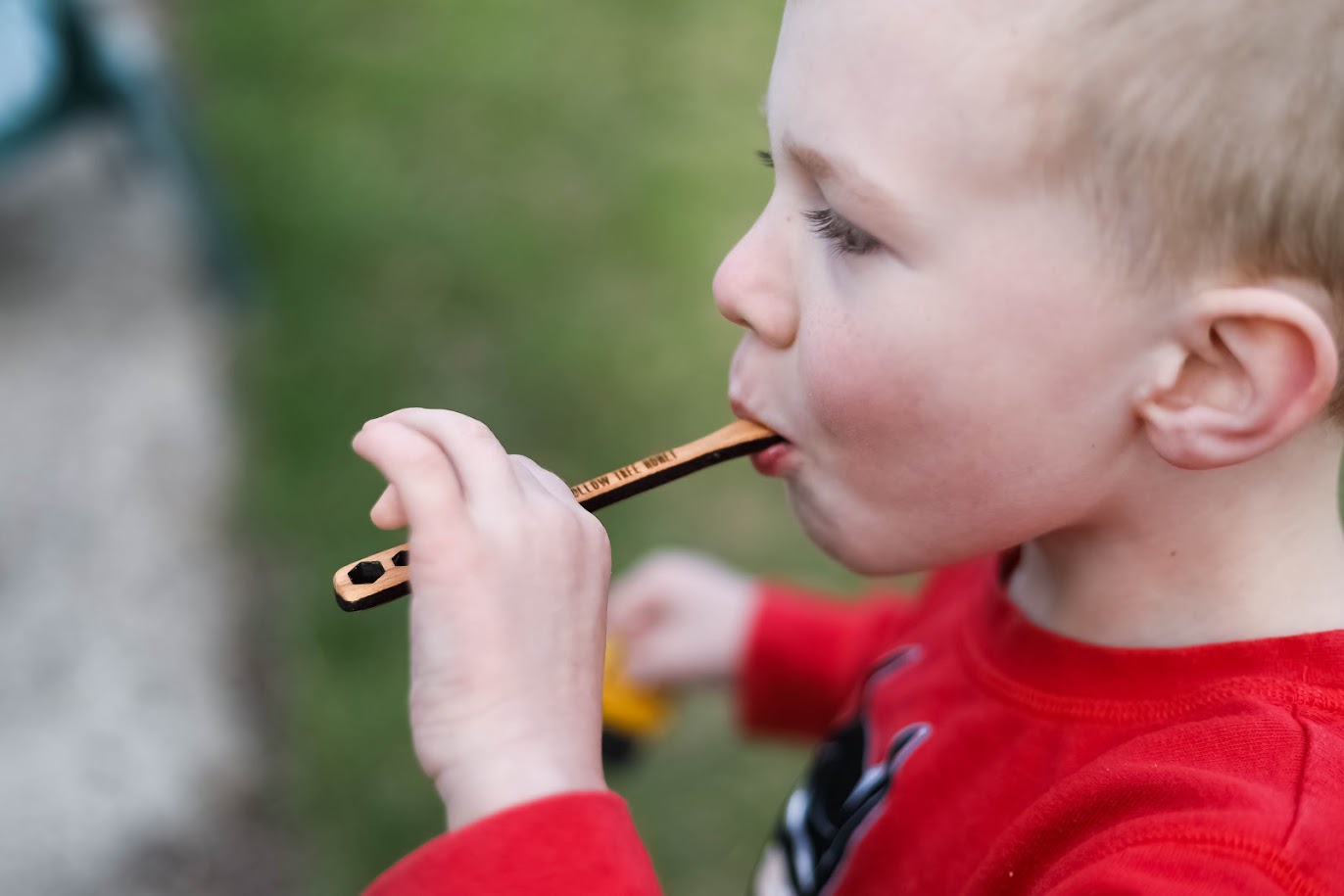 Child using honey dipper as a spoon to eat raw honey